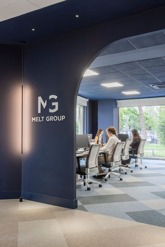 Acceso en arco azul marino con el logotipo de Melt Group y zona de trabajo abierta al fondo