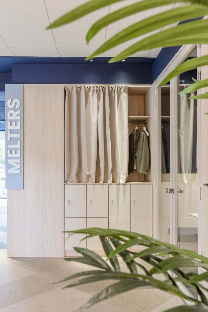 Taquillas de madera clara con cortinas y rótulo vertical Melters en las oficinas de Melt Group
