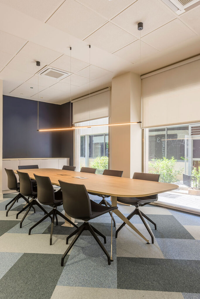 Sala de reuniones con mesa larga de madera y sillas negras en las oficinas de Melt Group