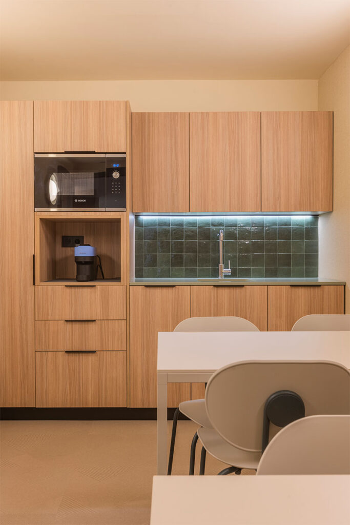 Office y comedor de las oficinas de Arisnova con muebles de cocina en madera y azulejo verde