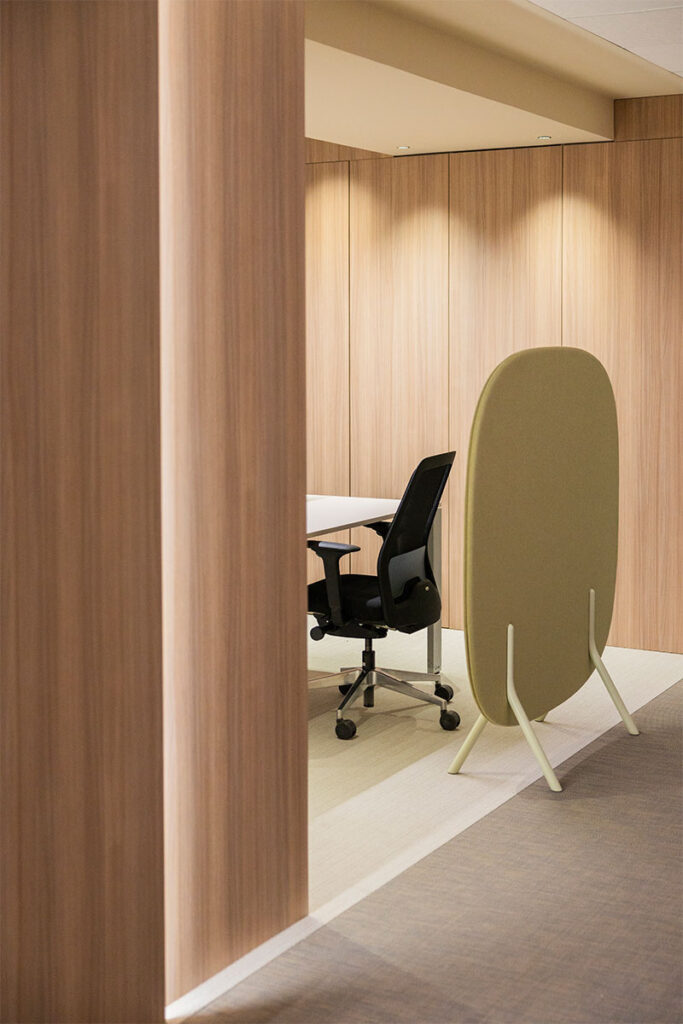 Puesto de trabajo individual con silla ergonómica y biombo acústico verde en las oficinas de Arisnova
